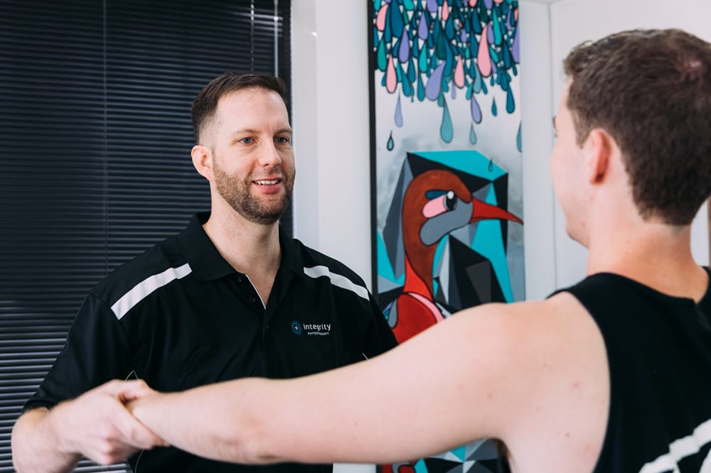 Physiotherapist at Integrity Physio in Como guiding a client through shoulder movement assessment during a one-on-one session.