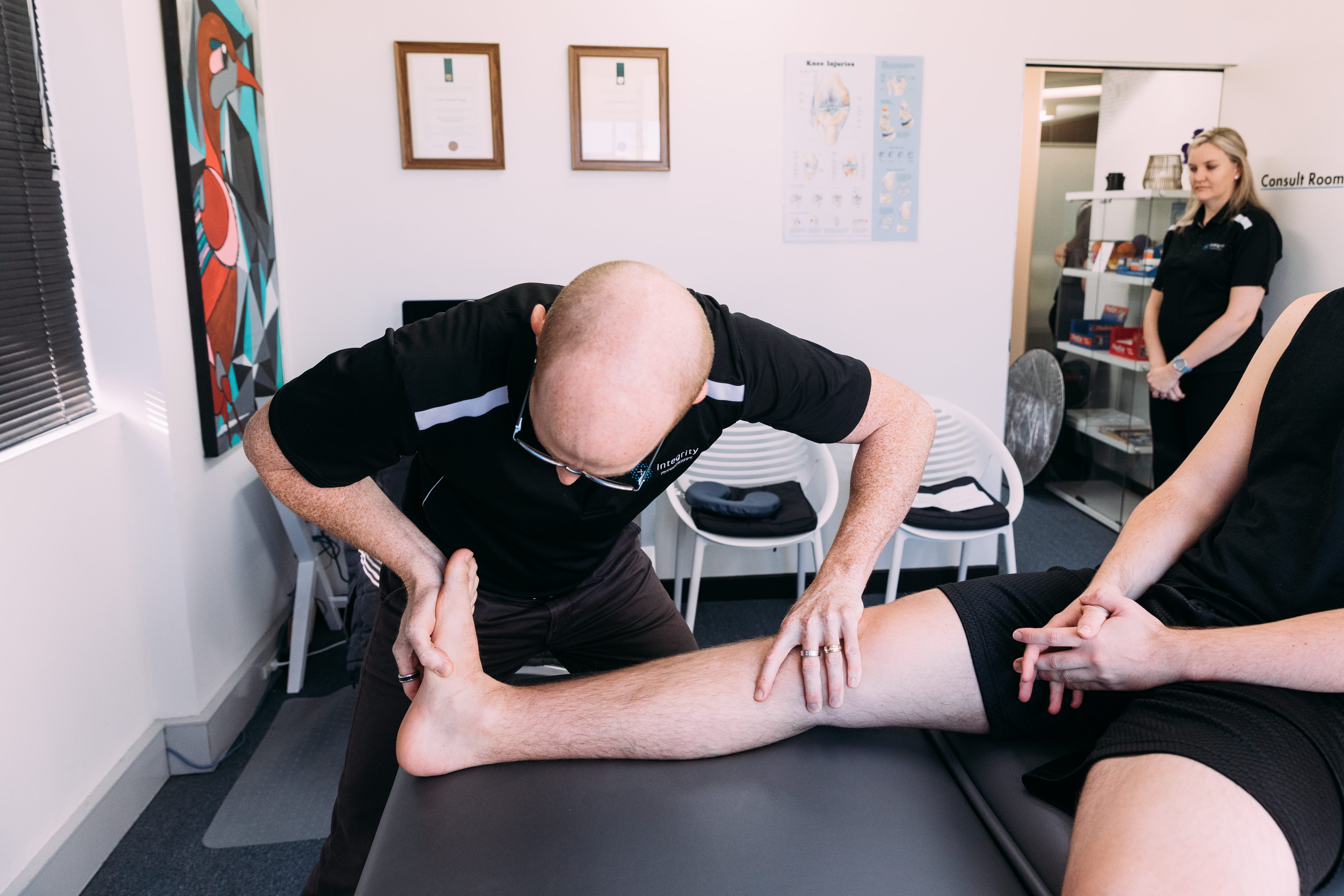 Leslie Trigg from Integrity Physiotherapy assessing a patient’s foot and lower leg.